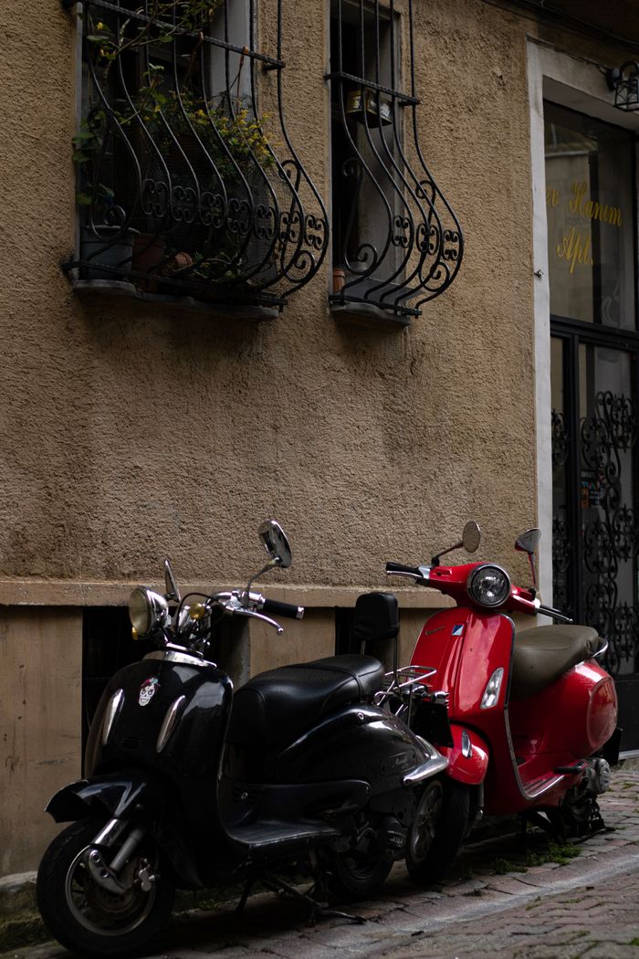 Charming urban alley with two scooters parked by a vintage apartment facade.